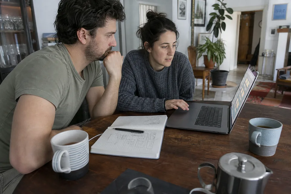 Engaged couple at a dining table comparing marriage preparation course options on a laptop