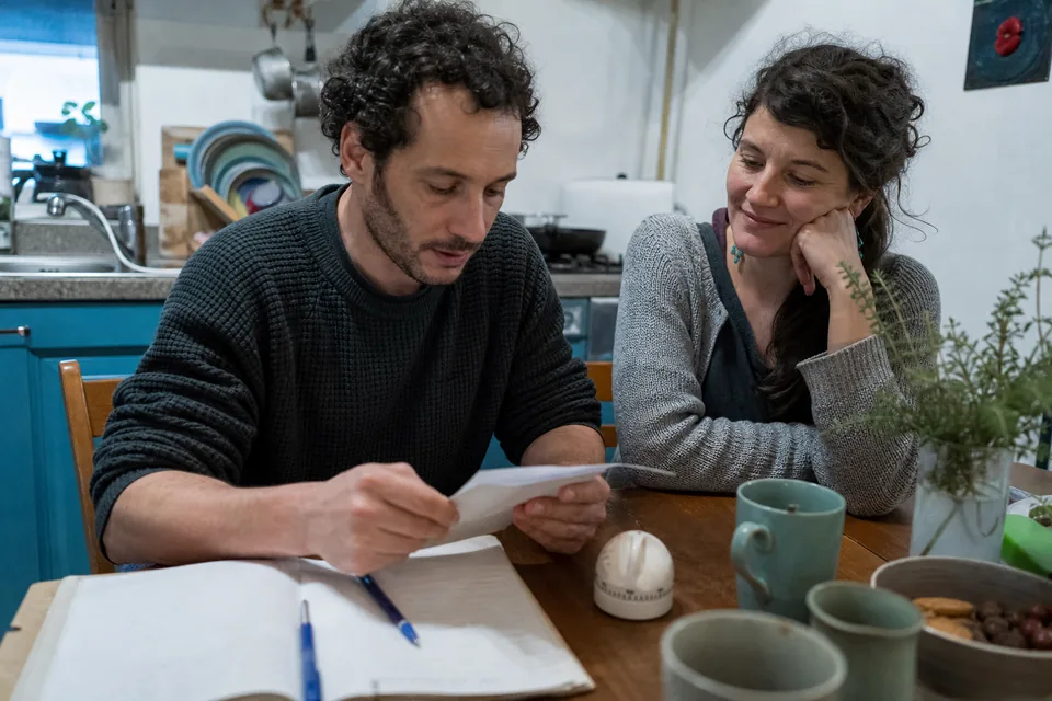Married couple doing their weekly exercise at the kitchen table with a notebook and a timer